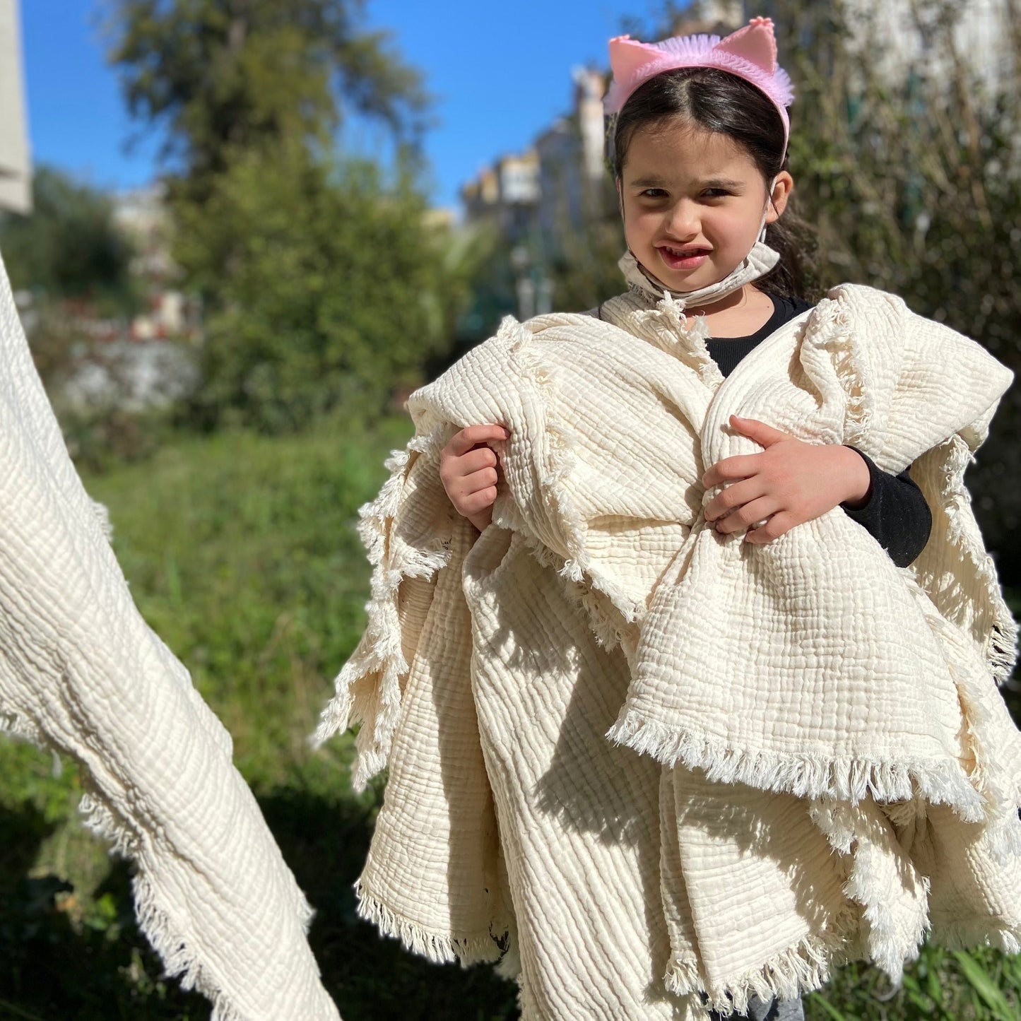 A baby holding multiple 8-layer crinkle gauze baby swaddle blankets, showcasing their variety and softness.