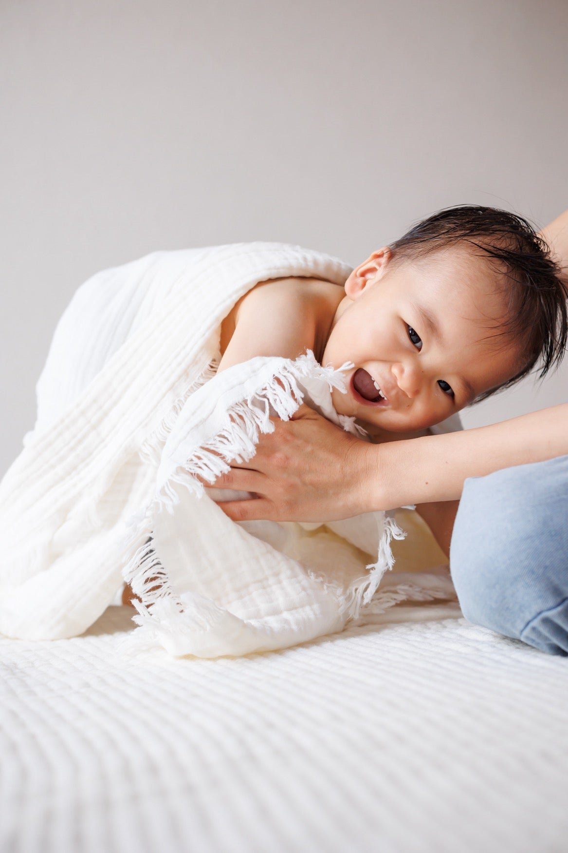 A mother uses a 100% cotton crinkle blanket to dry her baby after bath time