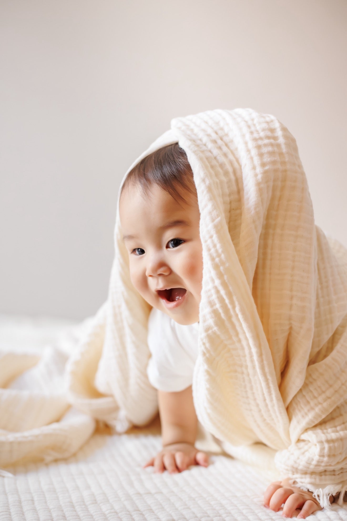 A baby holding the 8-layer crinkle gauze baby swaddle blanket, perfect for snuggling.