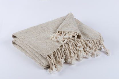 Folded handwoven peshtemal made from a cotton and linen blend, soft natural fabric with twisted fringe details