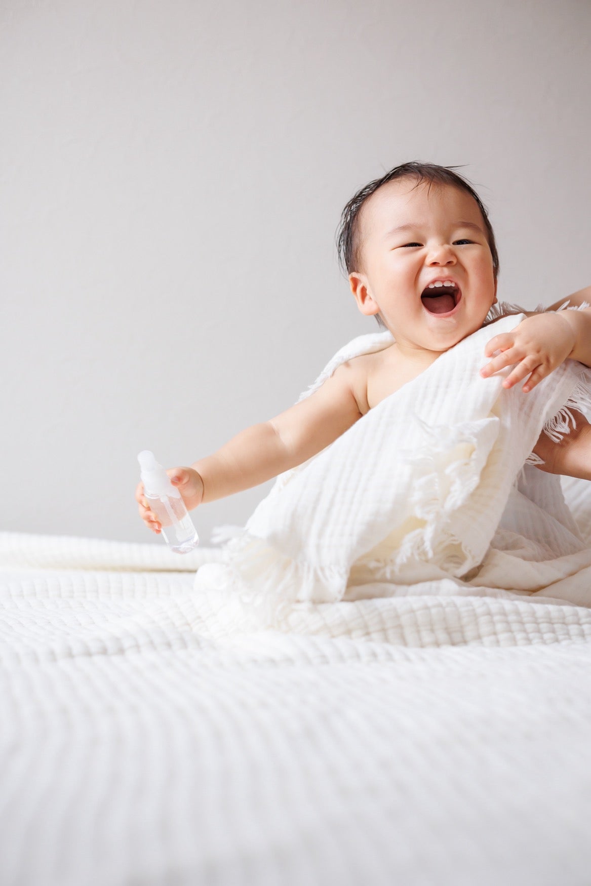 A mother gently dries her baby with a crinkle blanket after bath time.