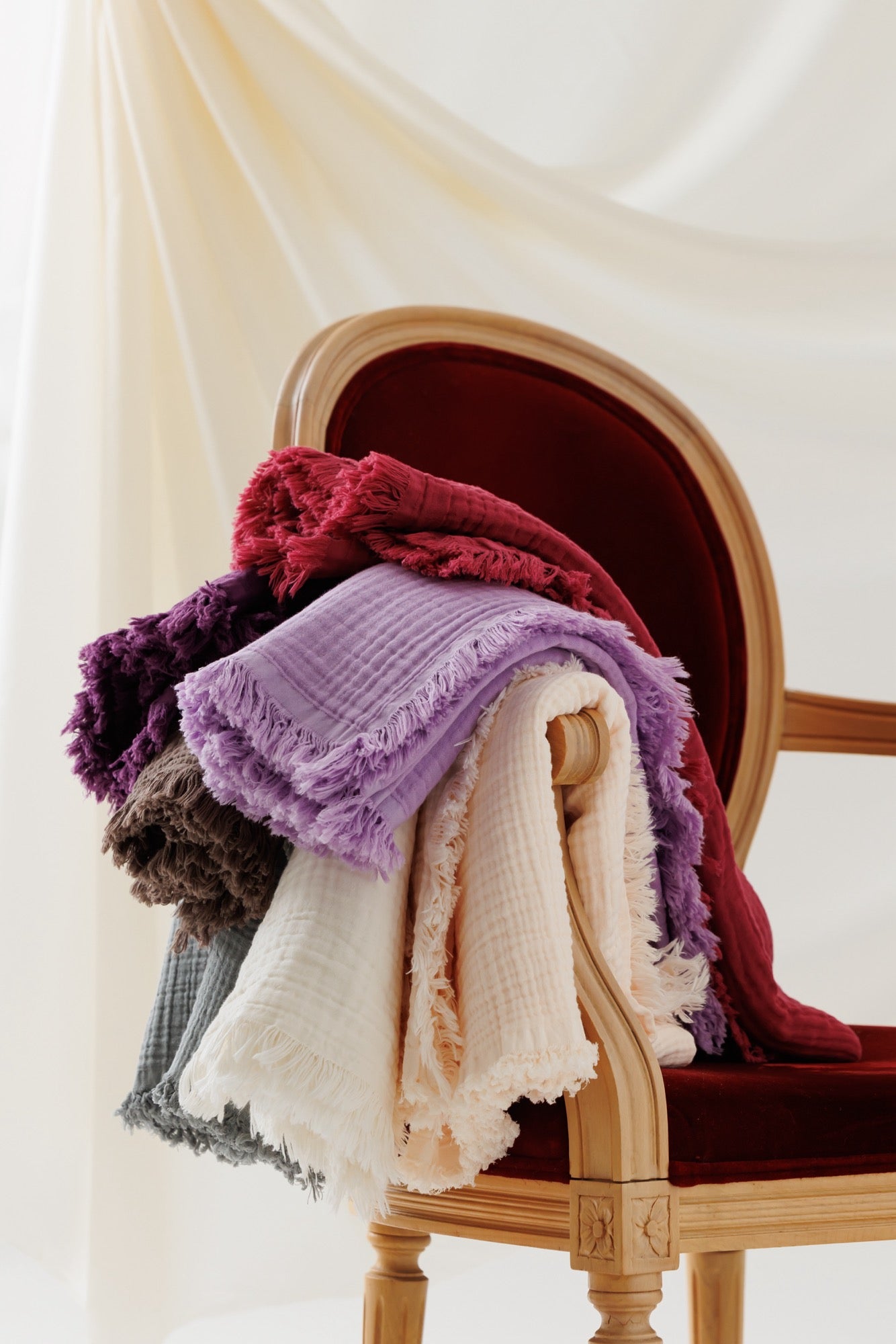 A collection of crinkle blankets in various colors displayed on a chair.