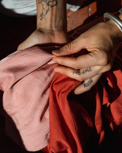 Hands holding naturally dyed fabric colored with madder root powder during the dyeing process