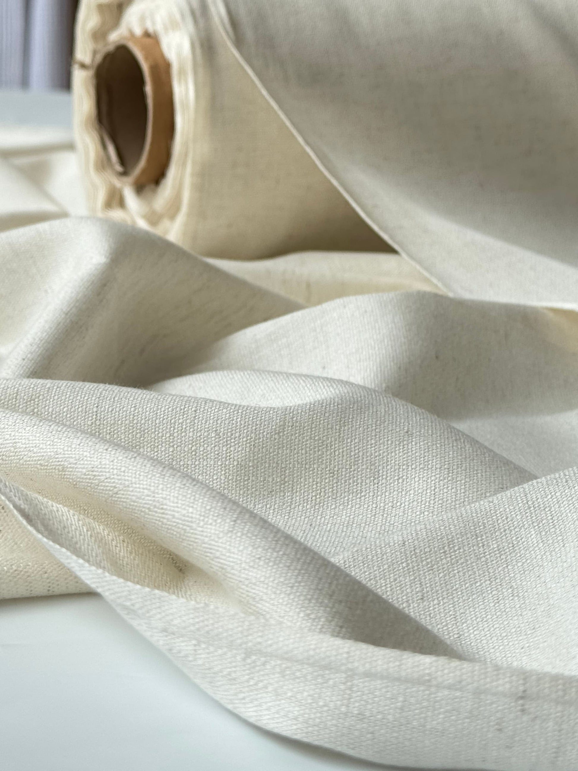 Close-up drape of undyed cotton linen fabric, lightweight and soft — suitable for apparel and home textiles