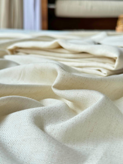Roll-end detail showing the natural weave of undyed cotton-linen fabric — subtle slubs and texture from semi-automatic handloom weaving