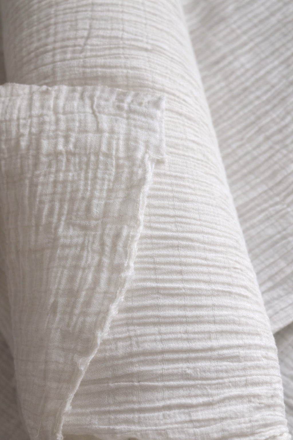 Close-up of undyed crinkle gauze cotton fabric showing vertical channel lines and natural texture, 61 in (155 cm) wide, dye-ready