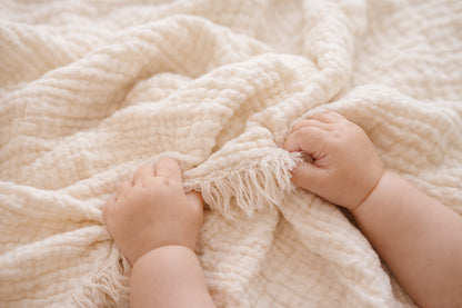 Close-up of the fringed edge and crinkled texture of our undyed 4-layer cotton muslin baby blanket, dye-ready.